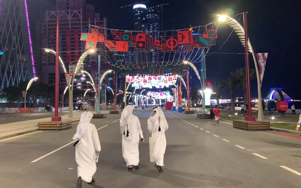 Des Qataris marchent dans la rue Corniche de Doha après la défaite de leur pays en match d'ouverture contre l'Équateur, le 20 novembre 2022. (Crédit : Ash Obel/Times of Israel)