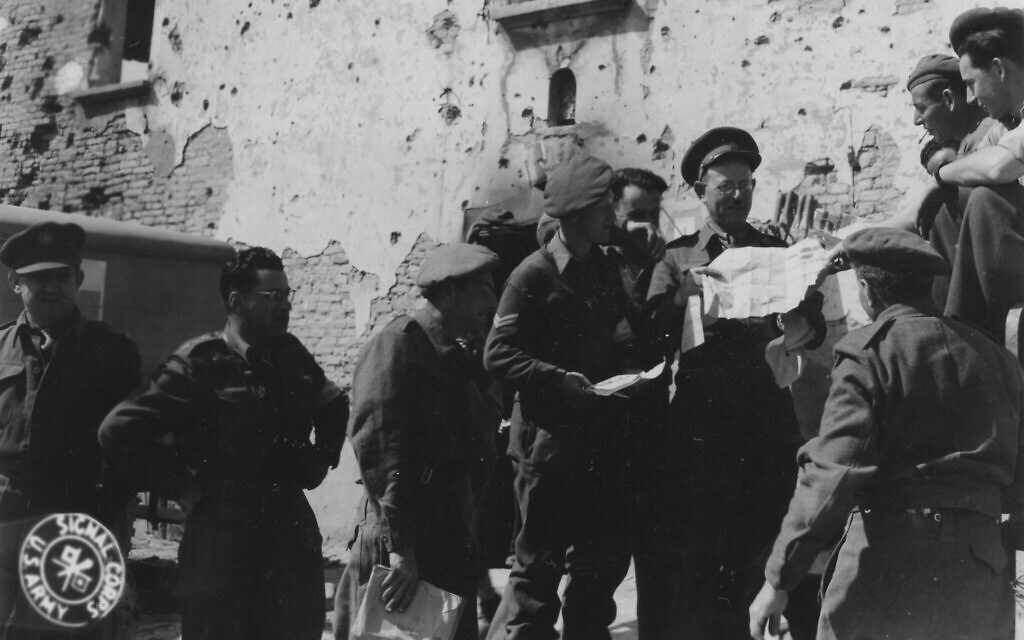 Le rabbin de la Brigade juive visitant un poste de secours en Italie et distribuant des journaux, en mars 1945. (Crédit : Levine, 196th Signal Photo Co./Signal Corps Archive from United States/Domaine public/Wikimedia Commons)