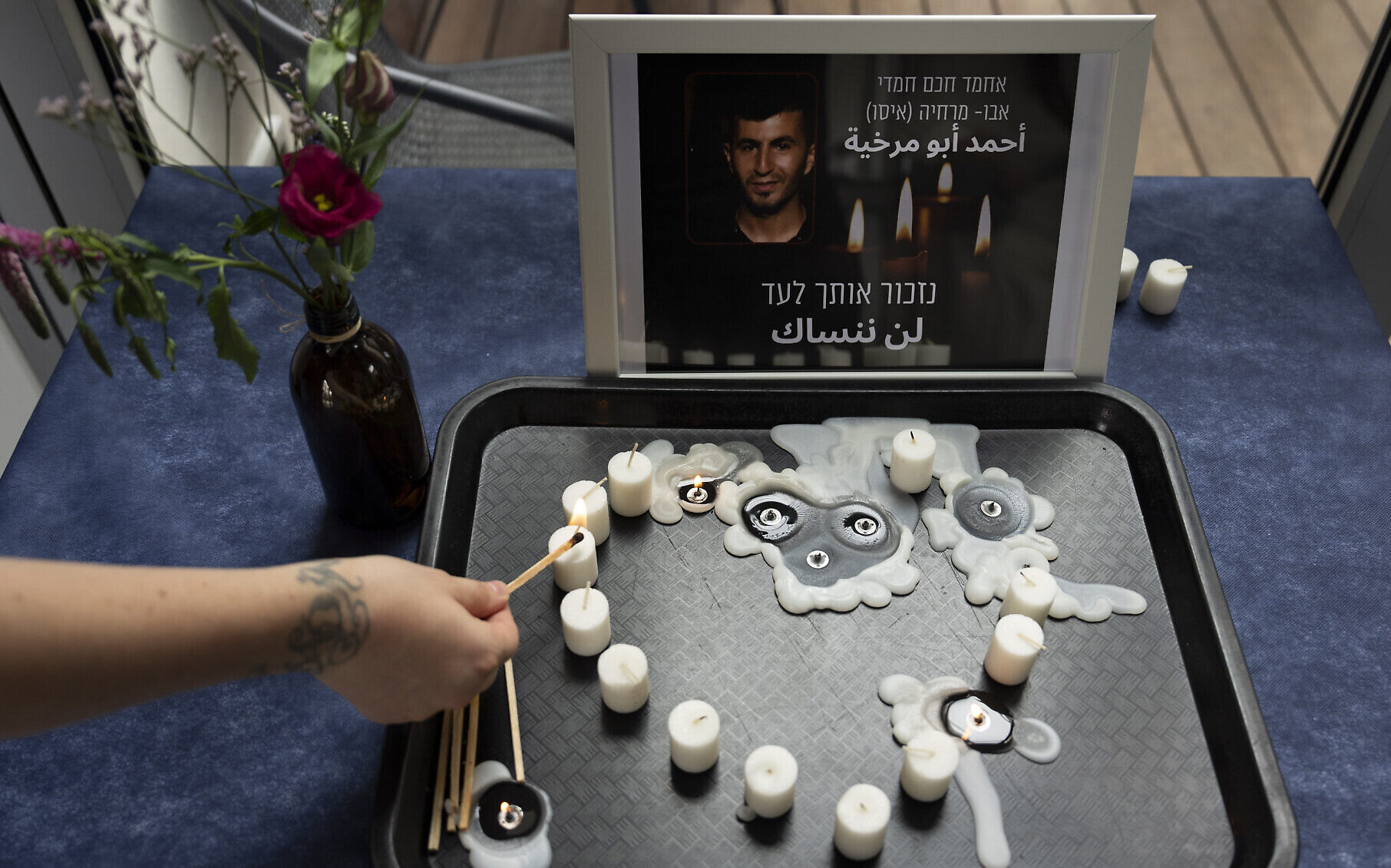 Un bénévole allume une bougie pendant une veillée en mémoire d'Ahmad Abu Murkhiyeh, un Palestinien de 25 ans qui a été retrouvé décapité à Hébron en Cisjordanie, dans un refuge LGBT de Tel Aviv, le 7 octobre 2022.  (Crédit : AP/Oded Balilty)