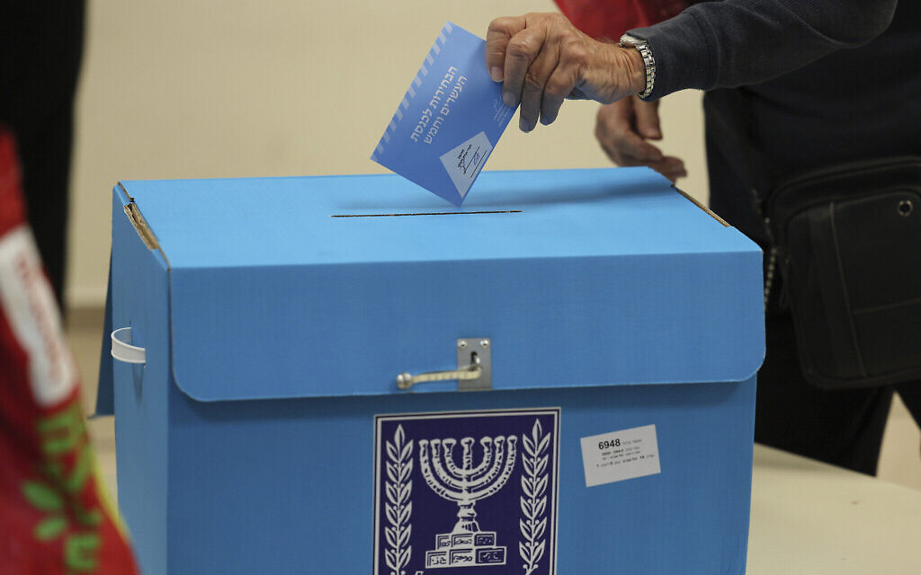 Un électeur israélien dépose un bulletin de vote lors de la cinquième élection d'Israël en moins de quatre ans dans un bureau de vote de Tel Aviv, le 1er novembre 2022. (Crédit : Jack Guez/Pool Photo via AP)