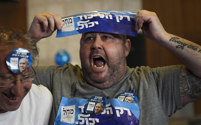 Un partisan de Benjamin Netanyahu connu sous le nom de Liran Grey-Shirt célébrant les sondages de sortie des urnes au siège du Likud à Jérusalem, le 1er novembre 2022. (Crédit : AP/Tsafrir Abayov)