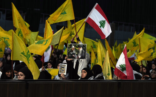Un partisan du Hezbollah tenant une photo du guide suprême iranien, l'ayatollah Ali Khamenei, à droite, et du général Qassem Soleimani, de la force Quds, tué par un drone américain à Bagdad, à gauche, lors d'un rassemblement marquant la Journée des martyrs du Hezbollah, au Liban, le 11 novembre 2022. (Crédit : AP Photo/Bilal Hussein)
