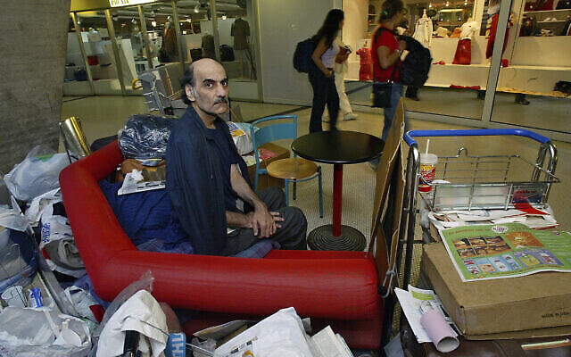 Merhan Karimi Nasseri est assis au milieu de ses affaires au Terminal 1 de l'aéroport Roissy Charles De Gaulle, le 11 août 2004. (Crédit : AP/Michel Euler, File)