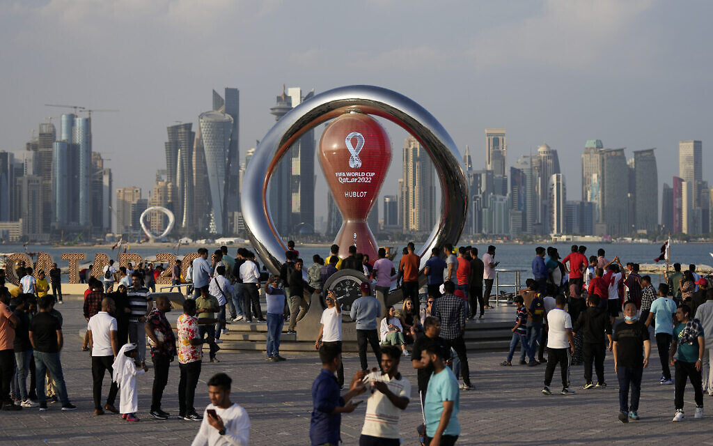 Des personnes rassemblées autour de l'horloge officielle du compte à rebours indiquant le temps restant avant le coup d'envoi de la Coupe du monde à Doha, au Qatar, le 11 novembre 2022. (Crédit : AP Photo/Hassan Ammar)