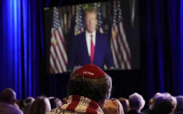 Des gens écoutent l’ex-président américain Donald Trump qui s'exprime à distance lors de la réunion annuelle de la Coalition juive Républicaine, le 19 novembre 2022, à Las Vegas. (Crédit : AP Photo/John Locher)