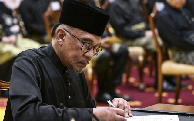 Le nouveau Premier ministre malaisien, Anwar Ibrahim, signe des documents lors de la cérémonie de prestation de serment au Palais national de Kuala Lumpur, en Malaisie, le 24 novembre 2022. (Crédit : Mohd Rasfan/Pool Photo via AP)