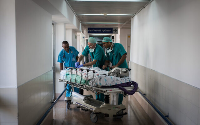 Illustration : Des médecins et des infirmières emmenant un enfant, transporté en Israël par Save a Child's Heart, en salle de réveil après que le nourrisson a subi une opération à cœur ouvert à l’hôpital Wolfson de Holon, en Israël, le 13 août 2018. (Crédit : Hadas Parush/Flash90)