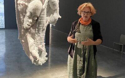 L'artiste Sigalit Landau avec l'un de ses filets de pêche, incrustés d'objets et recouverts de sel, lors de l'exposition "The Burning Sea", au Musée d'Israël jusqu'en juin 2023. (Crédit : Jessica Steinberg/Times of Israel)