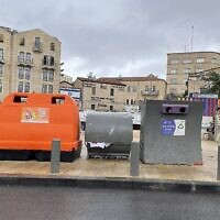Une poubelle orange pour le recyclage des déchets et des emballages près d'un conteneur à papier et d'une poubelle à verre, place  Hatulot, dans le centre de Jérusalem, le 27 novembre 2022. (Crédit : Sue Surkes/Times of Israel)