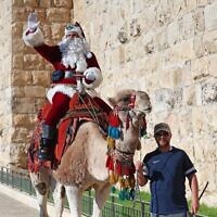 Le Palestinien Issa Kassissieh, habillé en père Noël, à dos de chameau à la porte de Jaffa dans la Vieille ville de Jérusalem, le 2 décembre 2022. (Crédit : AHMAD GHARABLI / AFP)