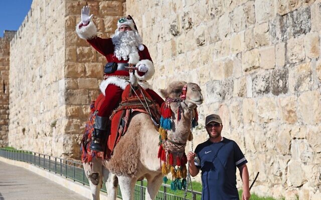 Le Palestinien Issa Kassissieh, habillé en père Noël, à dos de chameau à la porte de Jaffa dans la Vieille ville de Jérusalem, le 2 décembre 2022. (Crédit : AHMAD GHARABLI / AFP)