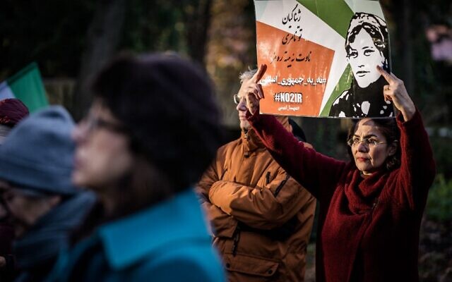 Un manifestant tient un slogan en persan disant "Non à la République islamique" et un autre slogan en kurde disant "Jina (Mahsa Amini), ma chère ! Tu ne mourras pas, ton nom deviendra un symbole" lors d'une manifestation devant la Chambre des représentants à La Haye, le 7 décembre 2022. (Crédit : Bart Maat / ANP / AFP)