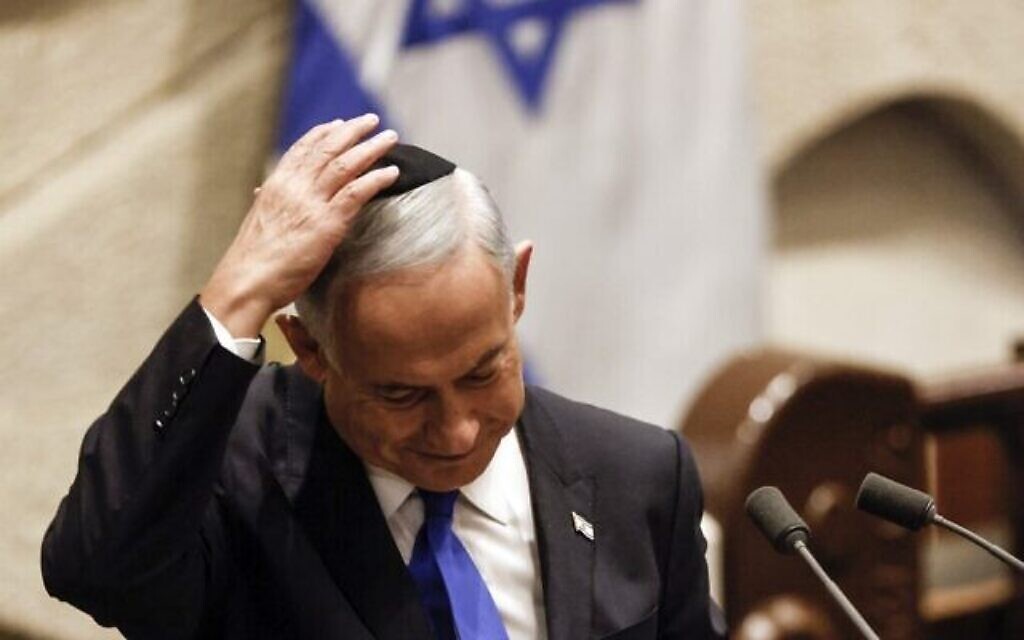 Le nouveau Premier ministre Benjamin Netanyahu met une kippa avant de réciter une bénédiction pour son nouveau gouvernement lors de son discours à la Knesset, le 29 décembre 2022. (Crédit : Amir Cohen / Pool / AFP)