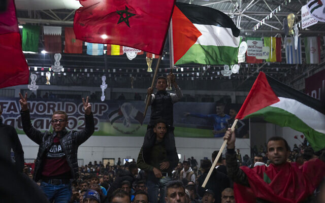 Des Palestiniens agitent des drapeaux marocains et palestiniens alors qu'ils regardent le match France-Maroc, demi-finale de la Coupe du monde de football au Qatar, dans la ville de Gaza, le mercredi 14 décembre 2022. (Crédit : AP/Fatima Shbair)