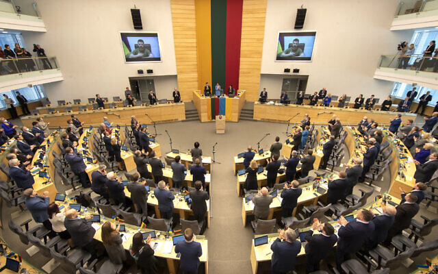 Les membres du parlement lituanien font une standing ovation au président ukrainien Volodymyr Zelensky avant un discours en visioconférence prononcé devant les députés au parlement de Vilnius, le 2 avril 2022. (Crédit :  AP Photo/Mindaugas Kulbis)