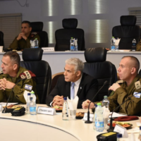 Le Premier ministre sortant, Yair Lapid, au centre, le chef d’état-major de Tsahal, Aviv Kohavi, à gauche, et le secrétaire militaire de Lapid, Avi Gil, au siège de Tsahal en Cisjordanie, le 4 décembre 2022. (Crédit : Haim Zach)