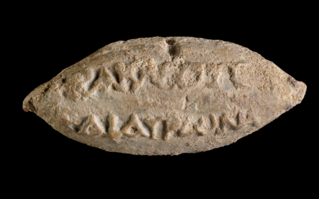 Les noms des dieux Héraclès et Hauron sur le revers d'une balle de fronde trouvée à Yavne. (Crédit : Dafna Gazit/Autorité israélienne des Antiquités)
