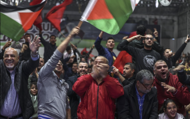 Des fans de football palestiniens brandissant des drapeaux nationaux et marocains pour célébrer la victoire du Maroc lors du huitième de finale de la Coupe du monde de football Qatar 2022 contre le Portugal, dans la ville de Gaza, le 10 décembre 2022. (Crédit : Mohammed Abed/AFP)