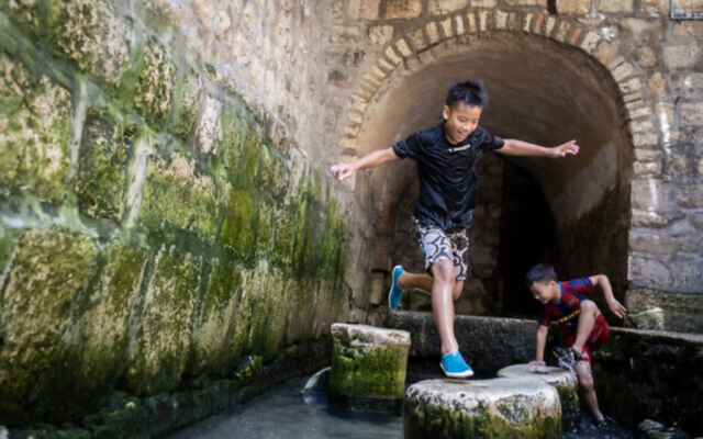 Illustration : De jeunes taïwanais jouant dans l'eau du bassin biblique de Siloé après avoir traversé le tunnel d'Ézéchias lors de leur visite du parc national de la Cité de David, le 28 juillet 2019. (Crédit : Hadas Parush/Flash90/Dossier)