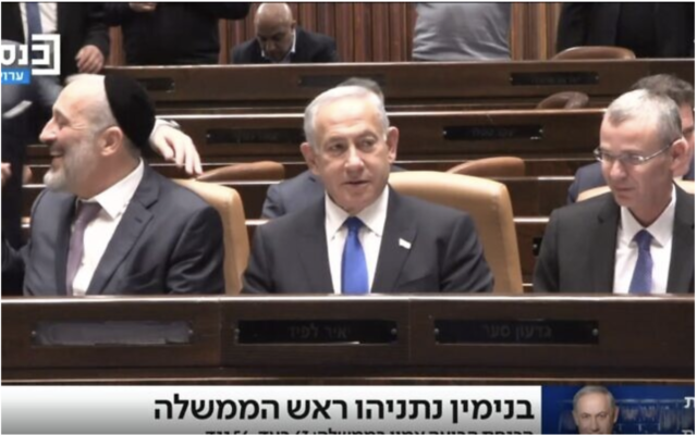 Le Premier ministre Benjamin Netanyahu prenant place sur le premier banc de la Knesset, entouré du vice-Premier ministre et ministre de l'Intérieur Aryeh Deri (du Shas), à gauche, et du ministre de la Justice Yariv Levin, quelques instants après que sa nouvelle coalition a prêté serment, le 29 décembre 2022. (Crédit : La chaîne Knesset)