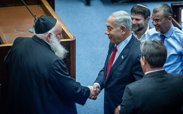 Le président du Likud, Benjamin Netanyahu, à droite, serre la main du chef du parti Yahadout HaTorah, Yitzchak Goldknopf, lors du plénum de la Knesset, le 21 novembre 2022. (Crédit : Yonatan Sindel/Flash90)