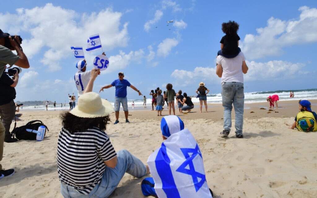 Des Israéliens sur la plage de Tel Aviv lors du spectacle aérien militaire du 74e jour de l'indépendance d'Israël, le 5 mai 2022. (Crédit : Avshalom Sassoni/Flash90)