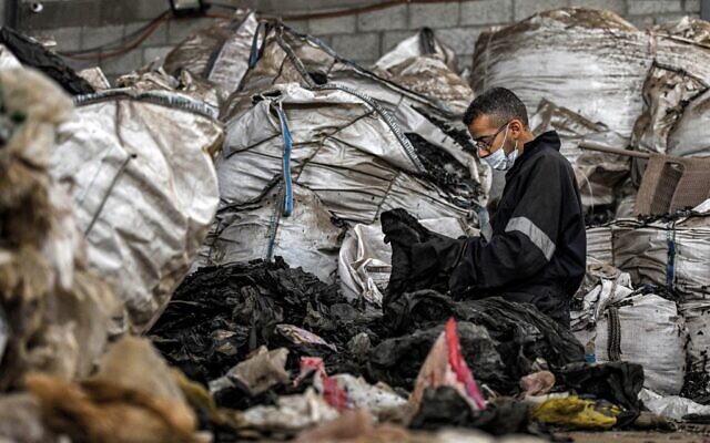 Un ouvrier trie des déchets plastiques dans un atelier de la startup "TileGreen", où ils sont recyclés en tuiles à emboîtement écologiques utilisées dans les allées extérieures, dans la cité industrielle Ashir min Ramadan, à environ 60 kilomètres à l'est de la capitale égyptienne, le 8 décembre 2022. (Crédit : Ahmed HASAN / AFP)