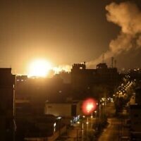 Du feu et de la fumée s’élèvant au-dessus des bâtiments de Gaza, suite aux frappes aériennes israéliennes sur l’enclave palestinienne en représailles à des tirs de roquettes contre Israël depuis la Bande de Gaza dirigée par le Hamas, à l'aube du 27 janvier 2023. (Crédit : Mahmud Hams/AFP)