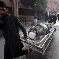 Des Pakistanais poussent une civière transportant une victime blessée, dans un hôpital de Peshawar, le 30 janvier 2023, après l'explosion la veille d'une mosquée située à l'intérieur du quartier général de la police de Peshawar, dans le nord-ouest du Pakistan. (Crédit : Zafar IQBAL/AFP)