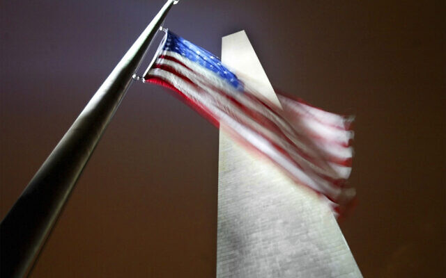 Un drapeau américain, le long du Washington Monument, flotte à mi-hauteur en mémoire des victimes du crash de la navette Columbia, à Washington, le 1er février 2003. (Crédit : Pablo Martinez Monsivais/AP)
