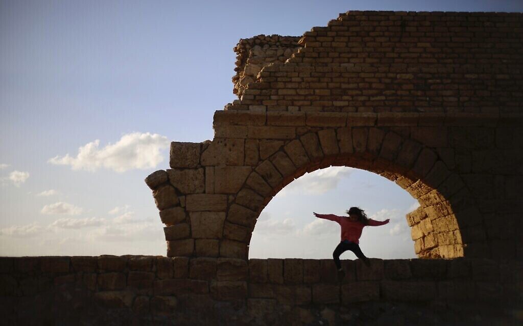 Une fille saute de l’ancien aqueduc de Césarée dans la mer Méditerranée, près du port de Césarée, en Israël, le 30 décembre 2019. (Crédit : AP Photo/Ariel Schalit)