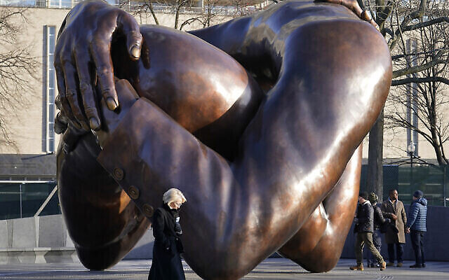 Des passants circulent à proximité de la sculpture en bronze de 6 mètres de haut baptisée « The Embrace » [L'Étreinte], monument en mémoire du Dr Martin Luther King Jr. et de Coretta Scott King, dans le parc de Boston Common, le 10 janvier 2023, à Boston. La sculpture, composée de quatre bras entrelacés, s'inspire d'une photo des Kings en train de s'embrasser, heureux d'apprendre que King vient de se voir décerner le prix Nobel de la paix en 1964. La statue a été dévoilée le 13 janvier 2023. (Crédit : AP/Steven Senne)