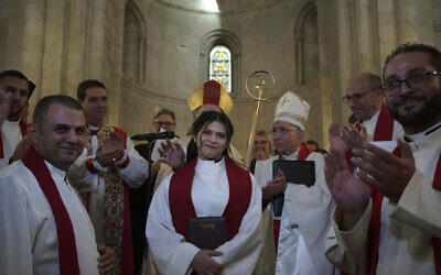 Sally Ibrahim Azar, au centre, une chrétienne palestinienne et membre du Conseil de la Fédération luthérienne mondiale, applaudie par le clergé après avoir été ordonnée première femme pasteur en Terre sainte, dans la Vieille Ville de Jérusalem, le 22 janvier 2023. (Crédit : AP/Maya Alleruzzo)