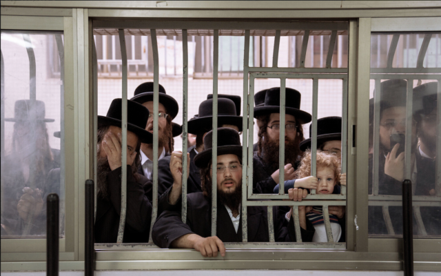 Des juifs ultra-orthodoxes regardant leur rabbin voter à Bnei Brak, le 1er novembre 2022. (Crédit : AP Photo/Oded Balilty)