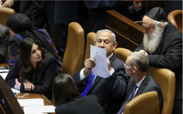 Le Premier ministre Benjamin Netanyahu s'entretenant avec d'autres membres importants de sa coalition au pouvoir lors d'une session plénière de la Knesset, le 16 janvier 2023. (Crédit : Noam Moskowitz/Knesset)