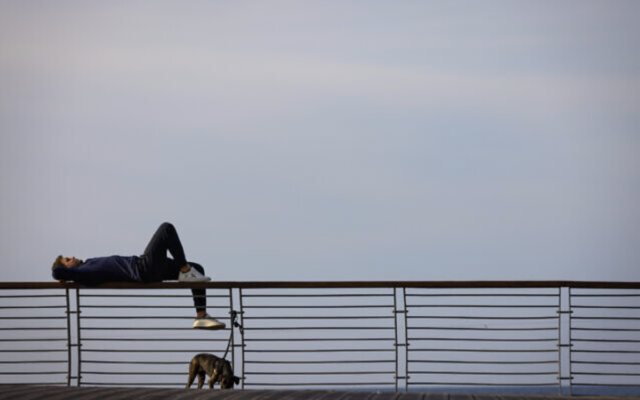 Un passant allongé sur une balustrade sur la promenade de Tel Aviv, au nord de la ville, le 11 janvier 2023. (Crédit : Olivier Fitoussi/Flash90)