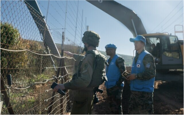 Un soldat israélien et des troupes de la FINUL inspectant une pelleteuse de Tsahal travaillant à la frontière avec le Liban, le 19 janvier 2023. (Crédit : Armée israélienne)