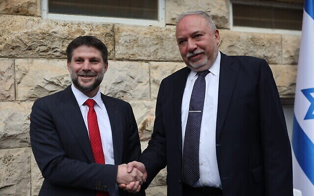 Le nouveau ministre des Finances, Bezalel Smotrich, à gauche, serrant la main du ministre sortant, Avigdor Liberman, lors de la passation de pouvoir au ministère des Finances, à Jérusalem, le 1er janvier 2023. (Crédit : Yonatan Sindel/Flash90)