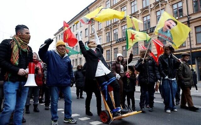 Des manifestants brandissent des drapeaux ornés de portraits d’Abdullah Ocalan, chef du Parti des travailleurs du Kurdistan (PKK), et défilent avec une effigie du président turc Recep Tayyip Erdogan, lors d’une manifestation organisée par le Conseil Démocratique Kurde contre la candidature d’Erdogan et de la Suède à l’OTAN, à Stockholm le 21 janvier 2023. (Crédit : Christine OLSSON/TT News Agency/AFP)
