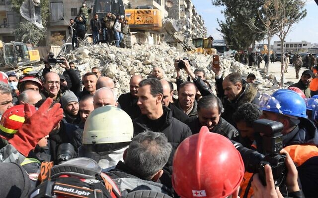 Le président syrien Bashar al-Assad salue la foule alors qu'il visite les quartiers touchés par un tremblement de terre dans la ville d'Alep, au nord du pays, le 10 février 2023. (Crédit : AFP)