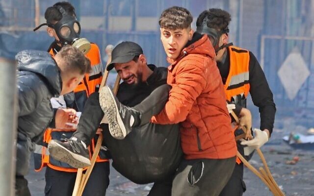 Des Palestiniens transportant un homme blessé lors d'une opération israélienne dans la ville de Naplouse, en Cisjordanie, le 22 février 2023. (Crédit : Zain Jaafar/AFP)