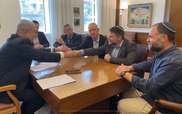 Le Premier ministre Benjamin Netanyahu serre la main du ministre des Finances, du ministre de la Défense Bezalel Smotrich (deuxième à partir de la droite), et du ministre de la Défense Yoav Gallant (troisième à partir de la droite), après la signature d'un accord transférant à Bezalel Smotrich les pouvoirs relatifs aux affaires civiles en Cisjordanie. (Crédit : Bureau du ministre des Finances)