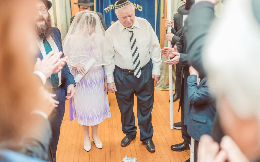 Un couple se prépare à marcher sur du verre, un symbole des mariages juifs, après leur cérémonie de mariage juif à Boston, le 7 février 2023. (Crédit : Igor Klimov via JTA)