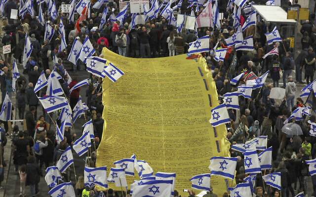 Des manifestants portant une énorme Déclaration d’Indépendance lors d'un rassemblement à Tel Aviv pour protester contre la révision du système judiciaire prévue par le gouvernement israélien, le 18 février 2023. (Crédit : Tomer Neuberg/Flash90)