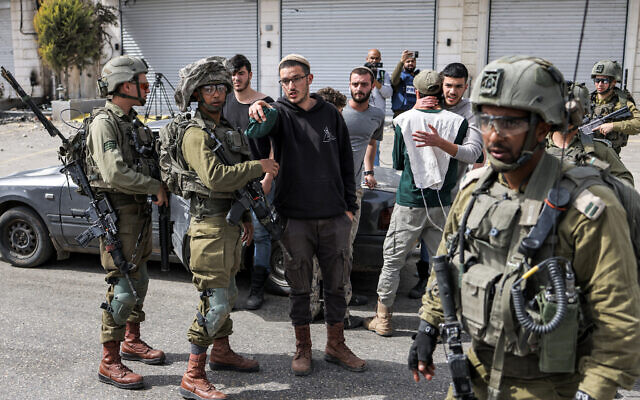 Des soldats israéliens parlant avec des résidents d’implantations dans la ville de Huwara, près de Naplouse, en Cisjordanie, le 27 février 2023. (Crédit : Ronaldo Schemidt/AFP)