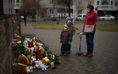 Illustration : Des gens rendent hommage aux victimes, devant un monument commémoratif improvisé sur les lieux où un hélicoptère s’est écrasé sur des immeubles, le 18 janvier à Brovary, en périphérie de Kiev, en Ukraine, le 20 janvier 2023. (Crédit : Daniel Cole/AP)