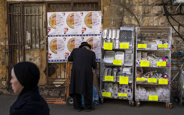 Un juif ultra-orthodoxe achetant de la vaisselle en plastique jetable dans le quartier de Mea Shearim, à Jérusalem, le 20 janvier 2023. (Crédit : Oded Balilty/AP)
