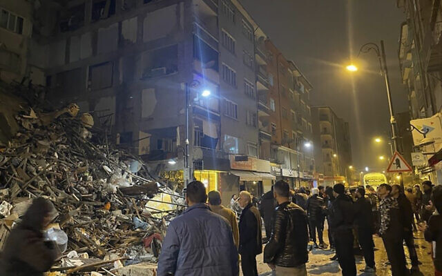 Des personnes se rassemblent autour d'un bâtiment effondré à Pazarcik, dans la province de Kahramanmaras, dans le sud de la Turquie, tôt le lundi 6 février 2023. (Crédit : Depo Photos via AP)