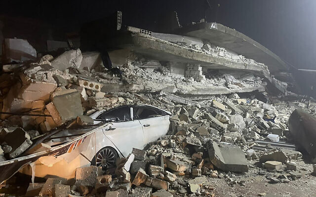 Une voiture sous les décombres d'un bâtiment effondré, dans la ville d'Azmarin, dans la province d'Idlib, au nord de la Syrie, le 6 février 2023. (Crédit : AP Photo/Ghaith Alsayed)