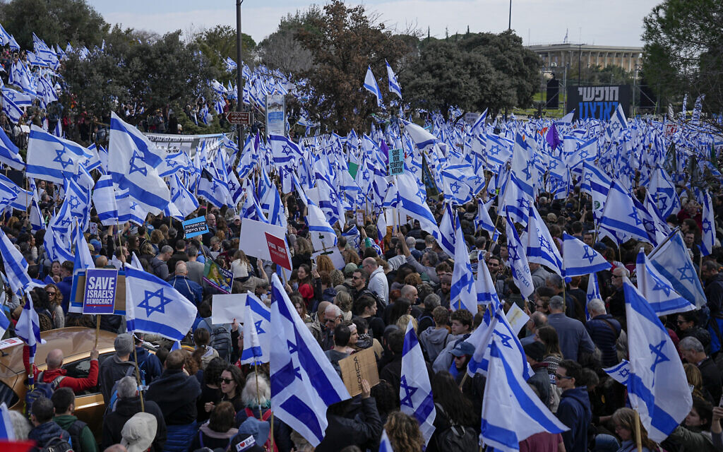 Des Israéliens brandissent le drapeau national lors d'un rassemblement contre la réforme judiciaire à la Knesset de Jérusalem, le 13 février 2023. (Crédit : AP Photo/Ohad Zwigenberg)